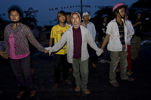 Residents hold hands, in a vain attempt to resist. (© Peter Harris - Fotojournalism.net)